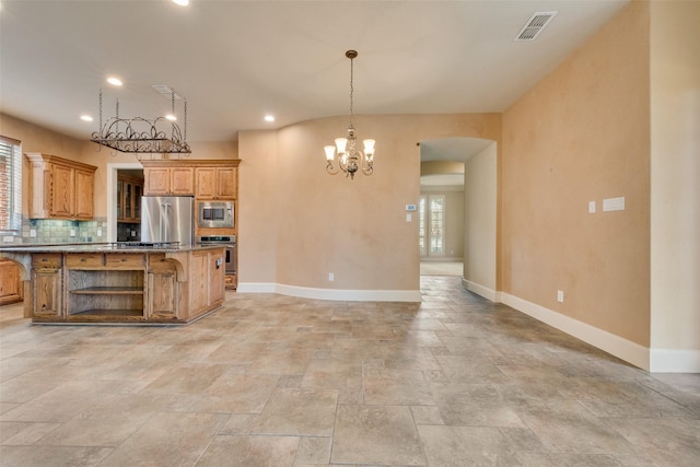 kitchen featuring stainless steel appliances, tasteful backsplash, dark stone counters, decorative light fixtures, and a kitchen bar