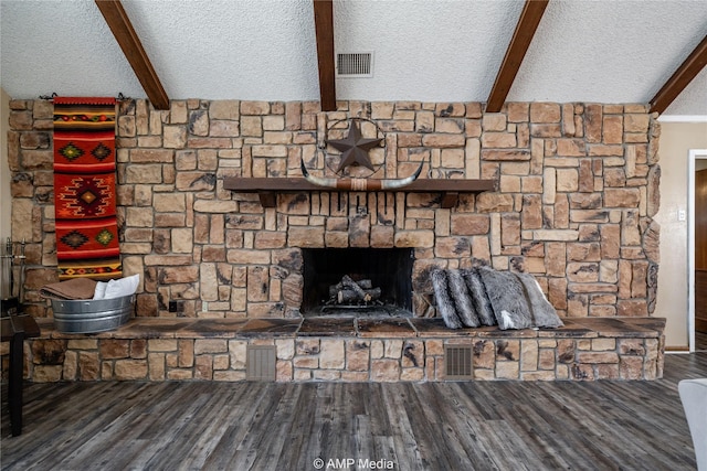 interior details featuring hardwood / wood-style flooring, a textured ceiling, beam ceiling, and a stone fireplace