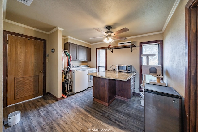 kitchen with washer and dryer, appliances with stainless steel finishes, a kitchen island, dark hardwood / wood-style floors, and dark brown cabinets