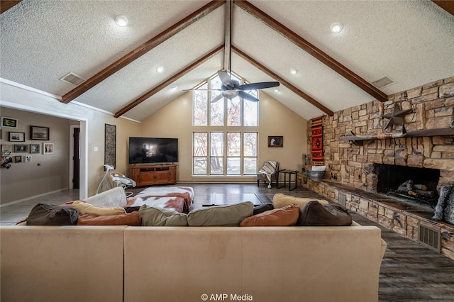 living room with a textured ceiling, hardwood / wood-style floors, beam ceiling, ceiling fan, and a stone fireplace