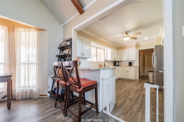 kitchen featuring white cabinets, tasteful backsplash, kitchen peninsula, and a breakfast bar area