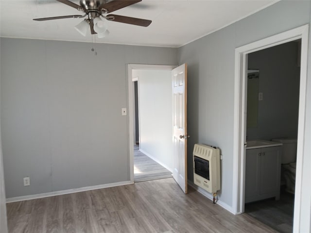 empty room featuring heating unit, ceiling fan, and light wood-type flooring