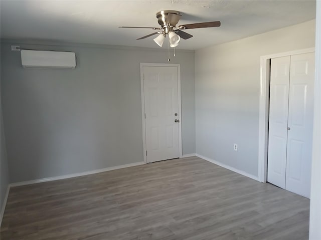 unfurnished bedroom featuring a wall mounted air conditioner, ceiling fan, and hardwood / wood-style flooring