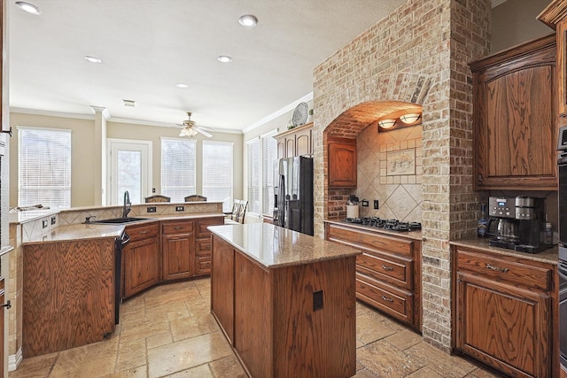 kitchen featuring refrigerator, a center island, stainless steel gas stovetop, ceiling fan, and sink