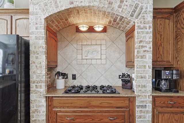 kitchen with light stone countertops, black appliances, and tasteful backsplash