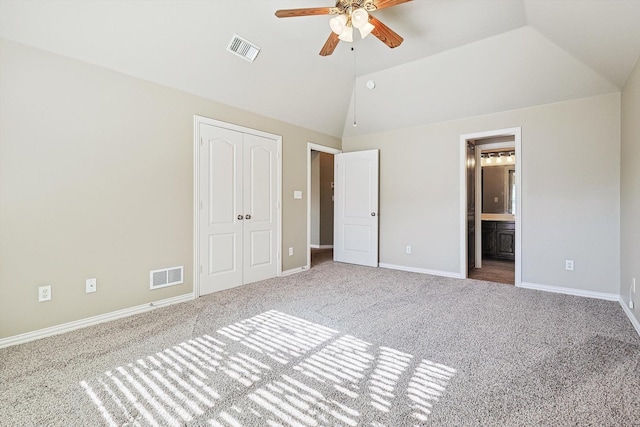 unfurnished bedroom with a closet, connected bathroom, lofted ceiling, carpet flooring, and ceiling fan