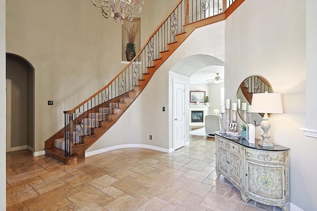 entryway featuring a towering ceiling and ceiling fan with notable chandelier