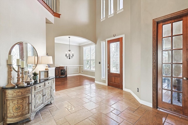 foyer entrance with a towering ceiling, an inviting chandelier, and ornamental molding