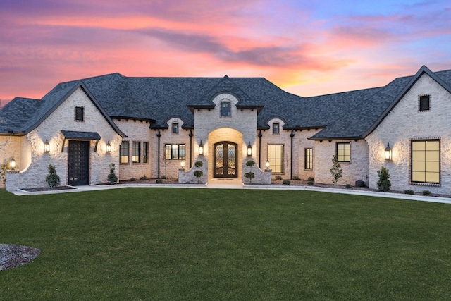 french country inspired facade featuring french doors and a lawn