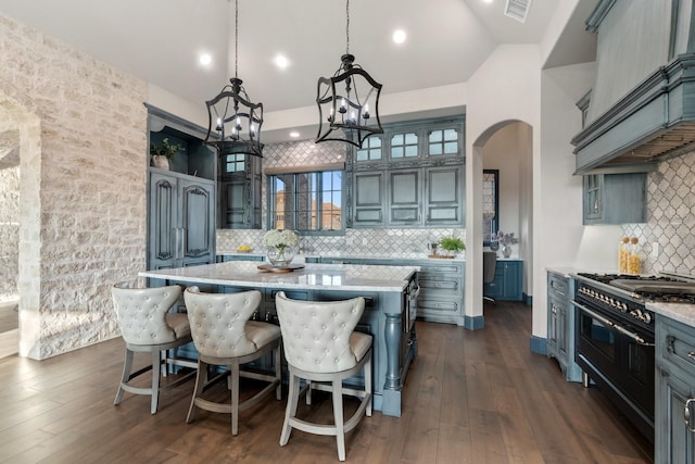 kitchen featuring hanging light fixtures, a center island, premium range hood, dark wood-type flooring, and double oven range