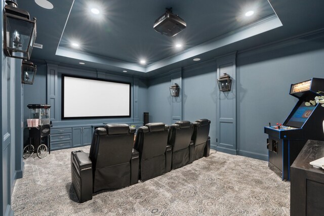 home theater featuring a raised ceiling, light colored carpet, and ornamental molding