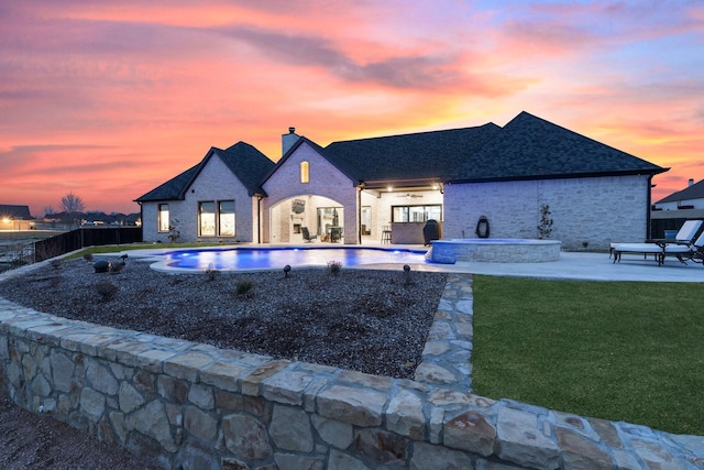 pool at dusk with a yard and a patio area