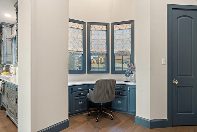 office with dark wood-type flooring, built in desk, and sink