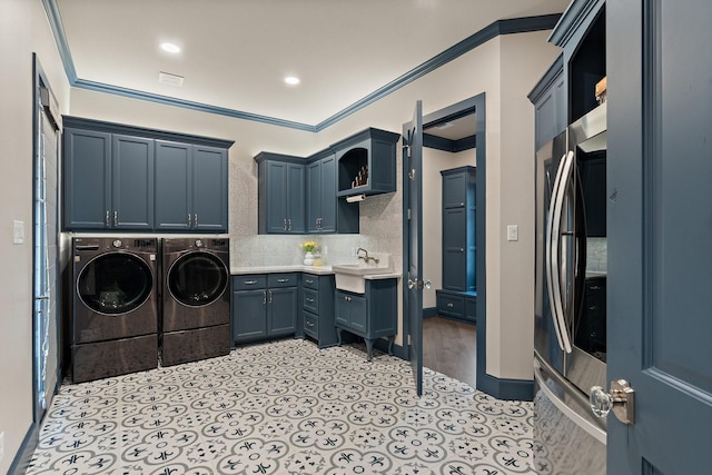 laundry room featuring sink, ornamental molding, cabinets, and independent washer and dryer