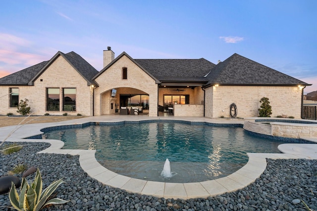 pool at dusk with a patio area, ceiling fan, and an in ground hot tub