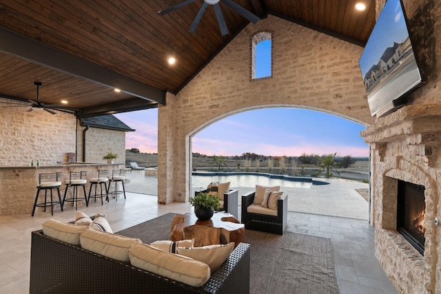 view of patio / terrace with an outdoor bar, ceiling fan, an outdoor living space with a fireplace, and a water view