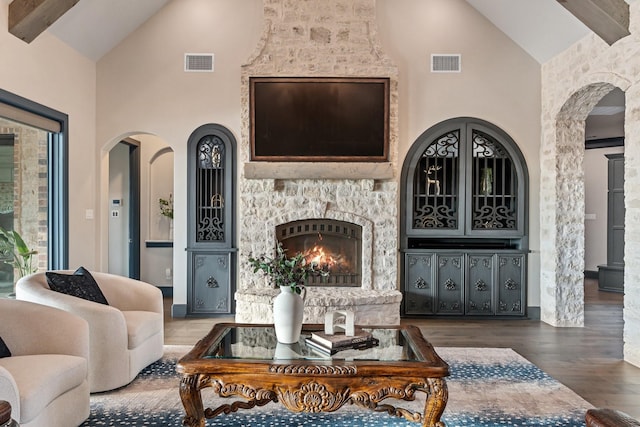 living room featuring beam ceiling, high vaulted ceiling, a fireplace, and hardwood / wood-style flooring