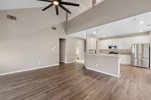 kitchen with tasteful backsplash, wood-type flooring, appliances with stainless steel finishes, and white cabinets