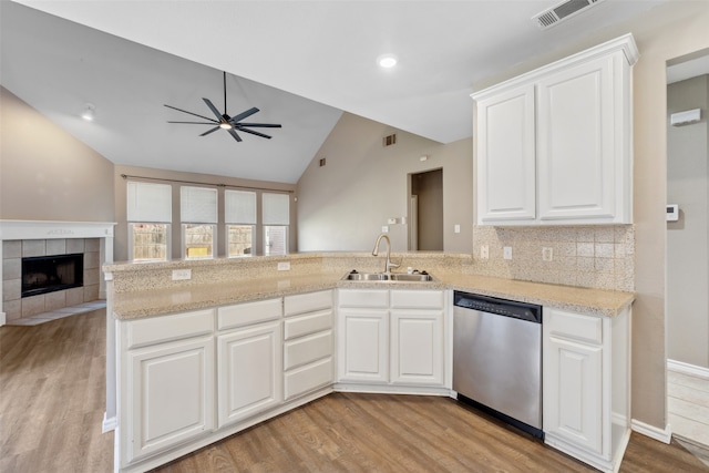 kitchen with vaulted ceiling, white cabinetry, sink, stainless steel dishwasher, and kitchen peninsula