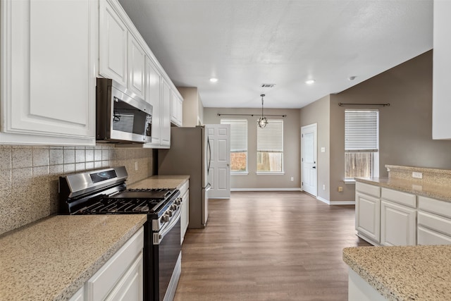 kitchen with white cabinetry, pendant lighting, light stone countertops, and appliances with stainless steel finishes