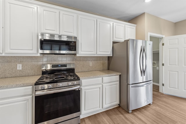 kitchen featuring backsplash, light hardwood / wood-style floors, white cabinets, and appliances with stainless steel finishes