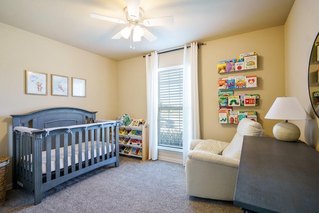 carpeted bedroom featuring ceiling fan and a nursery area