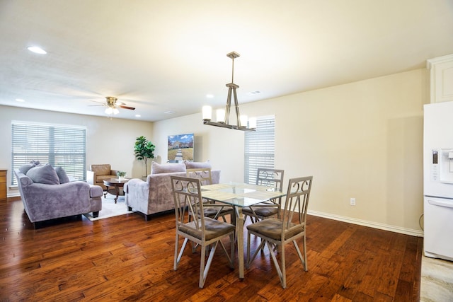 dining space featuring ceiling fan with notable chandelier and dark hardwood / wood-style flooring