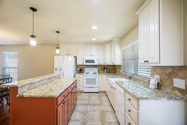 kitchen with white cabinets, a center island, white appliances, and sink