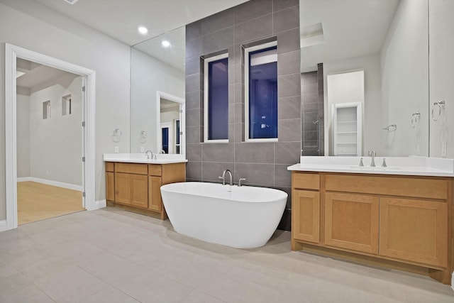 bathroom with tile patterned flooring, vanity, a bath, and tile walls