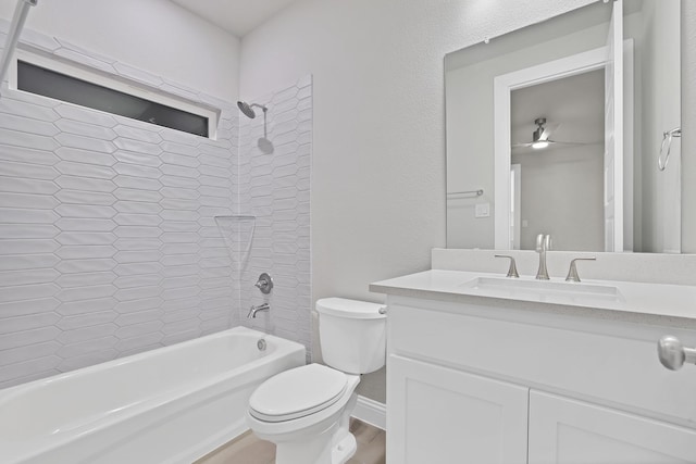 full bathroom with vanity, tiled shower / bath, hardwood / wood-style flooring, ceiling fan, and toilet