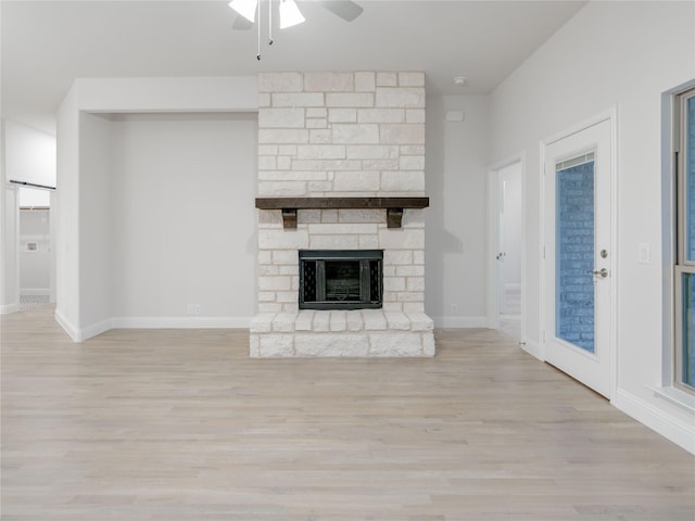 unfurnished living room with ceiling fan, a large fireplace, and light hardwood / wood-style floors