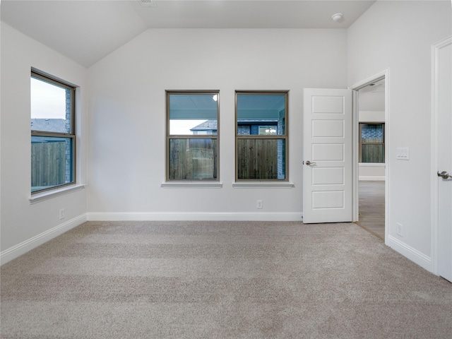 carpeted empty room with lofted ceiling