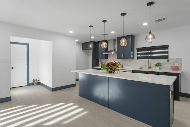 kitchen with wall chimney exhaust hood, light countertops, a sink, and decorative backsplash