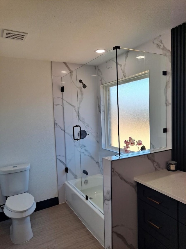 full bath featuring enclosed tub / shower combo, toilet, wood finished floors, vanity, and visible vents