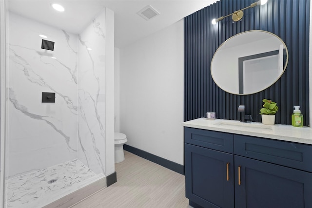 full bathroom featuring toilet, vanity, visible vents, baseboards, and a marble finish shower