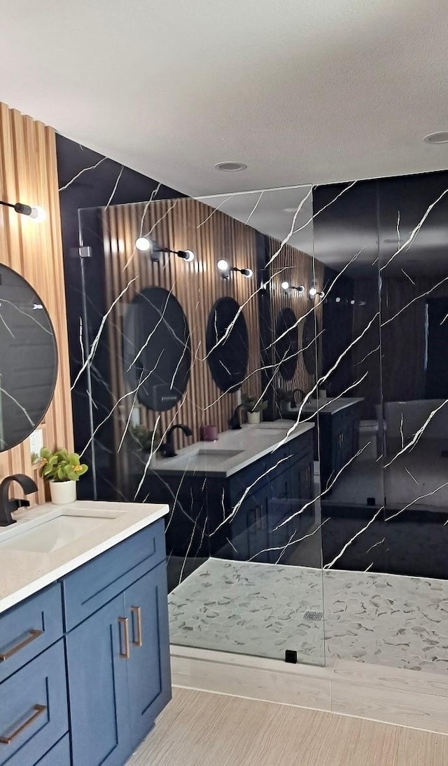 full bath with vanity, a marble finish shower, and a textured ceiling