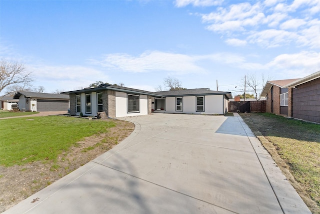 mid-century modern home with driveway, brick siding, fence, and a front yard