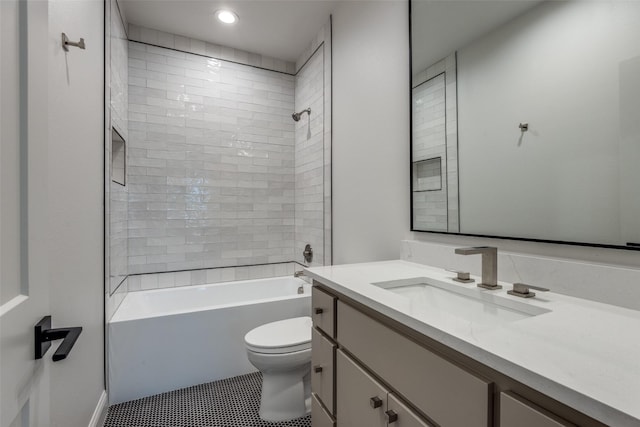 full bathroom featuring tile patterned flooring, tiled shower / bath, vanity, and toilet