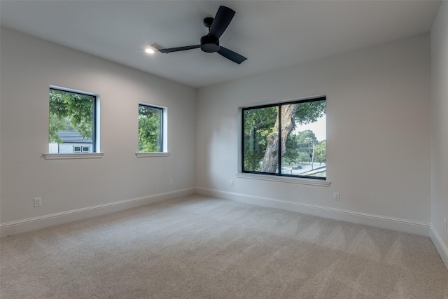 empty room featuring plenty of natural light, light colored carpet, and ceiling fan