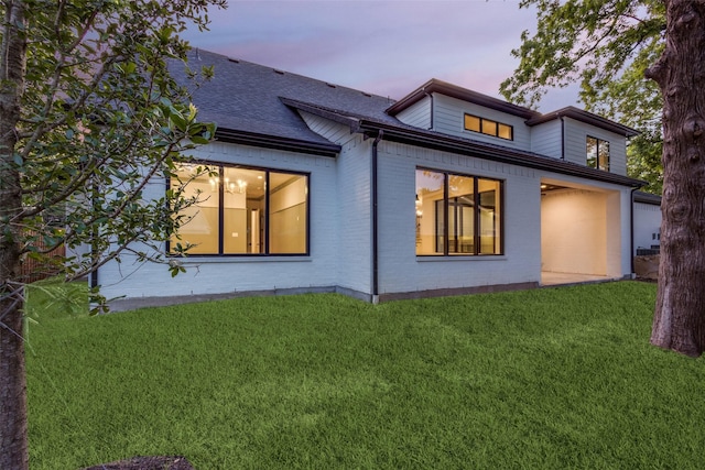 back house at dusk with a lawn