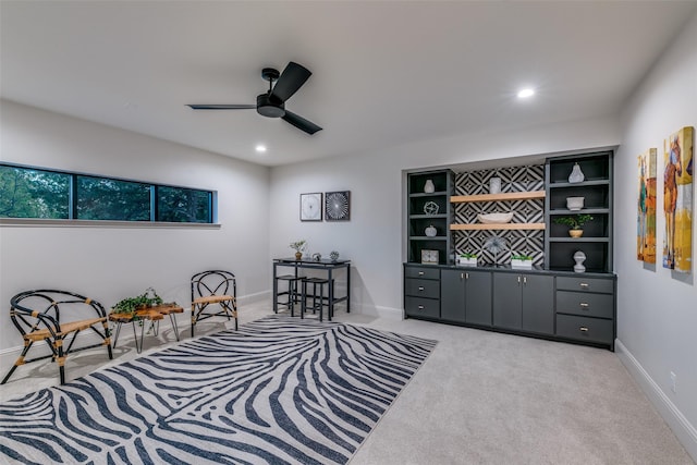 living area featuring light carpet, built in features, and ceiling fan