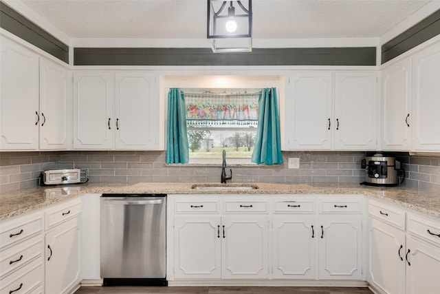 kitchen featuring tasteful backsplash, light stone countertops, stainless steel dishwasher, white cabinets, and sink