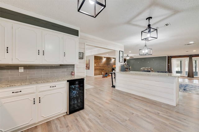 kitchen with pendant lighting, white cabinets, and wine cooler