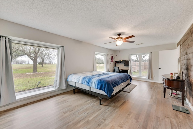 bedroom featuring a textured ceiling, ceiling fan, and light hardwood / wood-style floors