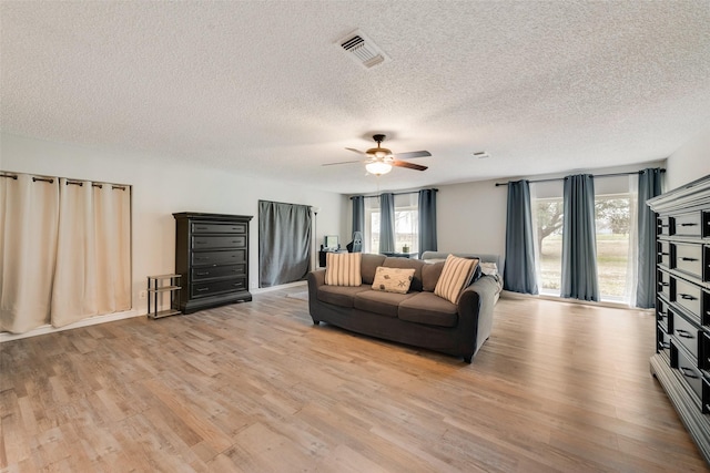 living room featuring light hardwood / wood-style floors, ceiling fan, and a textured ceiling