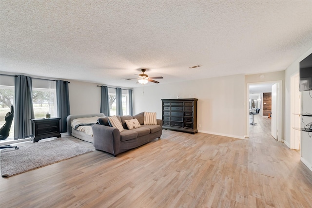 living room with ceiling fan, light hardwood / wood-style flooring, and a textured ceiling