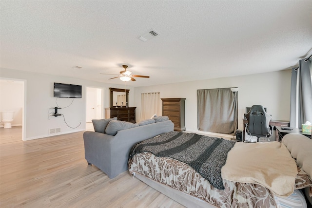 bedroom featuring ceiling fan, light wood-type flooring, a textured ceiling, and connected bathroom