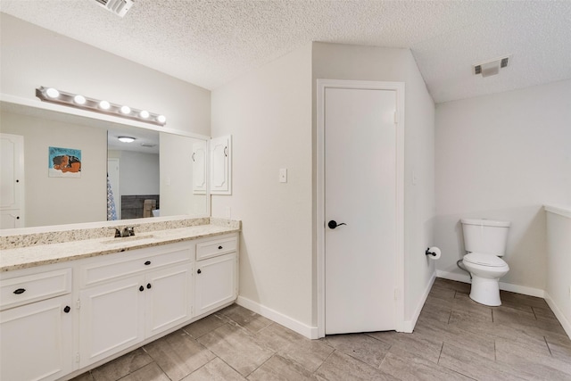 bathroom with a textured ceiling, toilet, and vanity