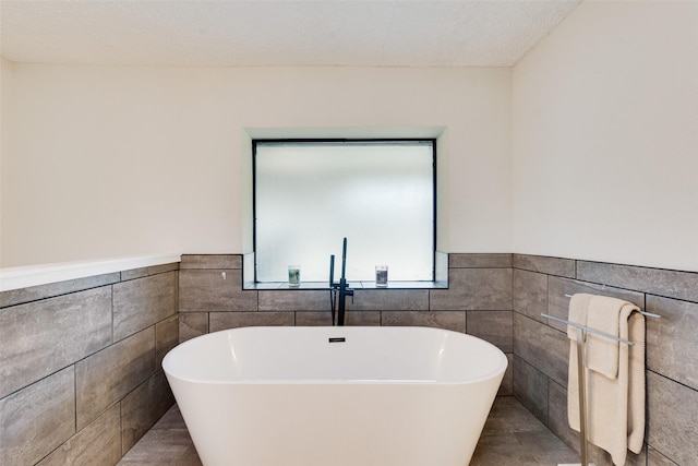 bathroom with tile patterned floors, a tub to relax in, and tile walls