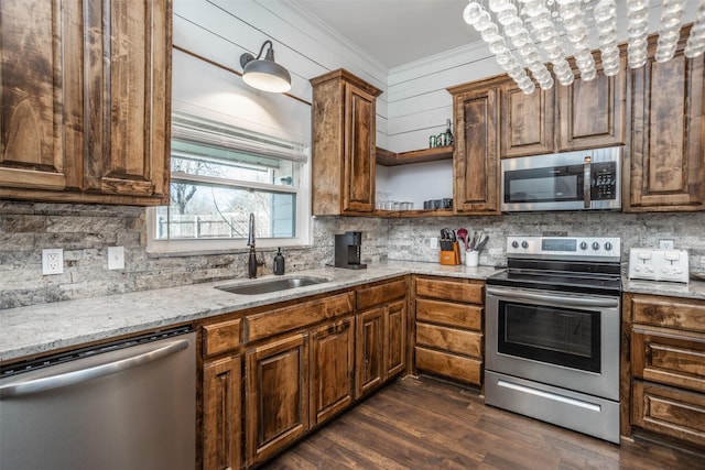 kitchen featuring sink, light stone counters, ornamental molding, appliances with stainless steel finishes, and decorative backsplash